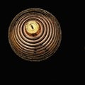 Close-up of golden brown striped christmas ball with sparkles on black background. Brown shiny striped ball on dark background.