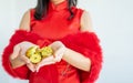 Close up on golden coins on hands of a woman wearing red qipao or dress to celebrate Chinese New Year, presenting about wealthy