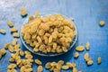 Close up of Golden raisins or Kishmish in a bowl on wooden surface.