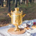 Golden russian samovar with tea cups and sweet snacks on table outdoor
