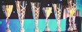 Close-up of golden trophies lined up at a dance event. Collection of trophies. Award cups close up