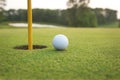 Close up of golf ball on a green near hole with pin Royalty Free Stock Photo