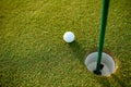 Close up of golf ball next to hole Royalty Free Stock Photo