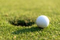 Close up Golf club hitting golf ball along with tee on green tee. Royalty Free Stock Photo