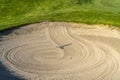 Close up of golf course sand bunker with a circular pattern created by the rake