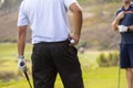 Close up of golfer holding golf ball and golf tee with another golfer in background