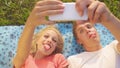 CLOSE UP: Goofy couple making funny faces while taking selfies for social media. Royalty Free Stock Photo