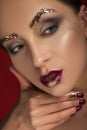Close up of a gorgeous a bit brutal woman with creative fashion make up: glitters and glamour shine. look