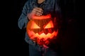 Close-up of gorgeous halloween pumpkin with burning and smoking mouth and eyes in female hands. Jack-o-lantern