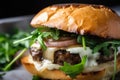 Close-up of a gourmet hamburger steak with caramelized onions, arugula, and garlic aioli on a toasted brioche bun Royalty Free Stock Photo