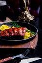 Close up Gourmet Main Dish with Grilled Pork Rib and Fried Potatoes on Black pan. Served on Wooden Board Royalty Free Stock Photo