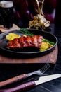 Close up Gourmet Main Dish with Grilled Pork Rib and Fried Potatoes on Black pan. Served on Wooden Board Royalty Free Stock Photo