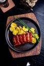 Close up Gourmet Main Dish with Grilled Pork Rib and Fried Potatoes on Black pan. Served on Wooden Board Royalty Free Stock Photo