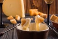 Close up. Gourmet Swiss fondue dinner on a winter evening with assorted cheeses on a board alongside a heated pot of cheese fondue Royalty Free Stock Photo