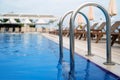 Close up of grab bars outdoor swimming pool entrance with sunlounger chairs terrace in the background Royalty Free Stock Photo