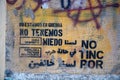 Close-up of a graffiti mural on a wall, featuring different phrases in different languages