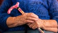 Close up of grandma holding a walking stick while she sitting on the sofa