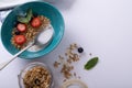 Close-up of granola with berry fruits, herbs and milk in bowl with spoon on table Royalty Free Stock Photo