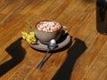 Hot chocolate in a cup on a table background. A sweet milk coffee with marshmallows, flowers, and a shadow of hands. Royalty Free Stock Photo