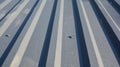 A close-up on a gray lightweight steel corrugated roofing sheet with stitching screws used to attach metal roofing to the wood