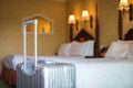 Close up gray silver travel suitcase is in an unoccupied hotel room and there is white linen cover.