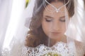 A close-up of the Greek bride covered her face with a white veil and lowered her big eyes down.