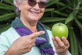 Close-up of a green apple holding by a senior smiling woman.  Concept of healthy eating and diet Royalty Free Stock Photo