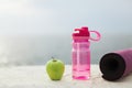 Close up green apple,sport bottle and yoga mat over fuzzy background