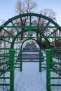 Close up of a green arch pergola in Kadriorg park on a sunny day. Stair with steps going up. Snowy weather during winter