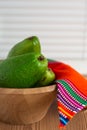 Close-up of green avocados in wooden bowl with red ethnic cloth, on wooden table and white background Royalty Free Stock Photo