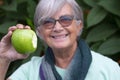 Close-up of a green bitten apple holding by a senior smiling woman.  Concept of healthy eating and diet Royalty Free Stock Photo