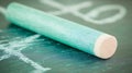 A close up of a green chalk stick resting on a chalkboard with chalk markings visible on the surface Royalty Free Stock Photo