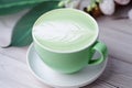 Close-up of a green coffee cup with a feather latte art design