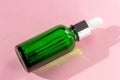 Close-up of a green cosmetic bottle on a pink background