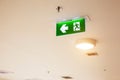 Close up the green emergency fire exit sign or fire escape on the building ceiling for doorway