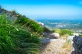 Green grass near tourist trail to mausoleum of Njegos against Cetinje city and blue sky background. Lovcen National Park. Royalty Free Stock Photo