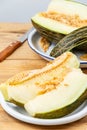 Close-up of green melon slices in white plate on wooden table, with half a melon, selective focus, Royalty Free Stock Photo