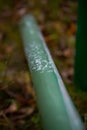 Close-up of a green metal pipe construction with abraded paint and shining metal