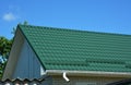 Close up on green metal roof with white, plastic rain gutter system. Royalty Free Stock Photo