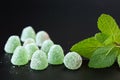 Close up of green, mint jelly drops with sugar crystals and spearmint leaves on a black background