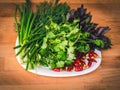 Close up of green organic herbs, basil, coriander, fennel, green onion, red chili peppers on white plate, rustic wooden background Royalty Free Stock Photo