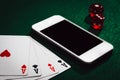 Close up of a green poker table with a smartphone, cards and dices. Winning money online Royalty Free Stock Photo