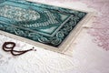 Close-up green prayer rug and rosary, praying in the month of ramadan