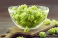 Close up of green ripe hop cones in a glass bowl over dark rustic wooden background. Beer production ingredient. Royalty Free Stock Photo