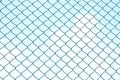 Close up green square wire mesh chain link fence against blue sky white clouds Royalty Free Stock Photo