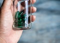 Close up green vitamins or supplements in the small clear glass bottle vials in person`s hand. Royalty Free Stock Photo