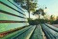 Close up of green wooden bench in urban park during sunset time. Royalty Free Stock Photo