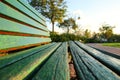 Close up of green wooden bench in urban park during sunset time. Royalty Free Stock Photo