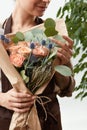 Close-up of greeting flowers bouquet of fresh natural roses living coral color in a florist girl`s hands on a white