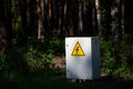 Close up Grey Hinged Power Supply Box in the wood. electrical box with yellow danger warning sign. electricity in remote Royalty Free Stock Photo